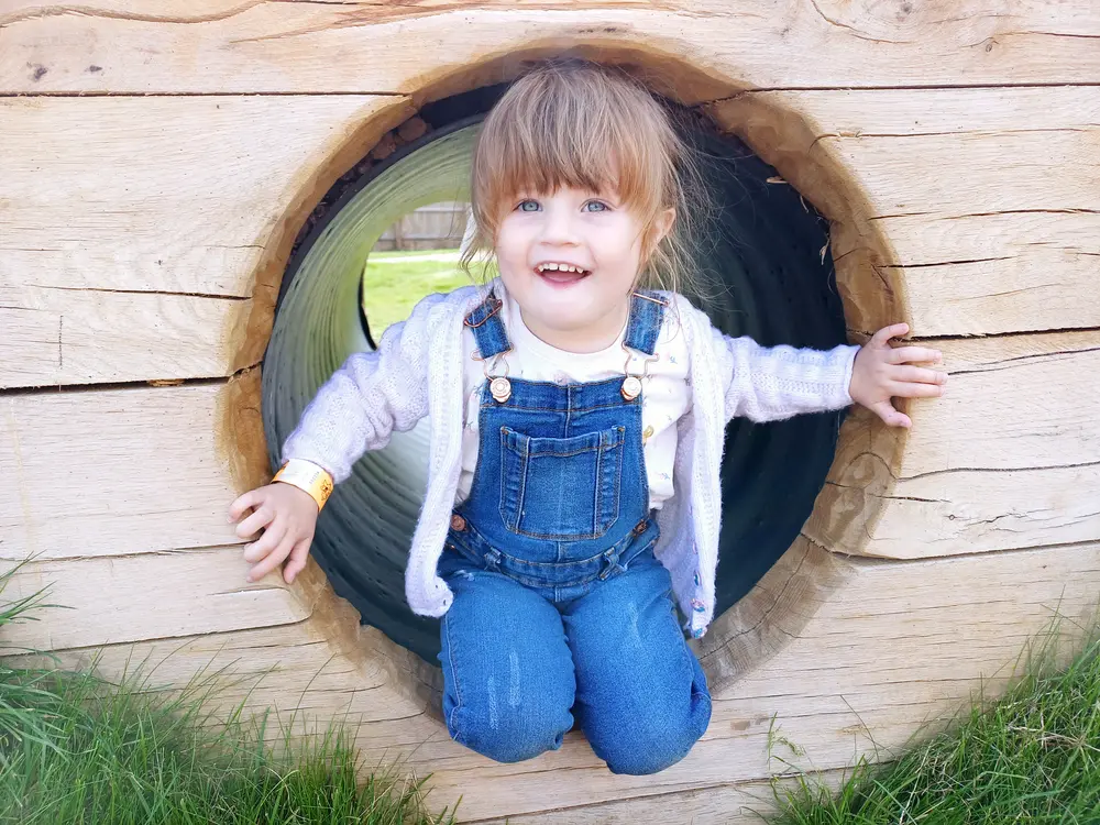 Little girl smiling as she comes out of tunnel in adventure playground